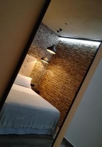 een kamer met een bed en een bakstenen muur bij Alvarado Loft Rural in Ubrique