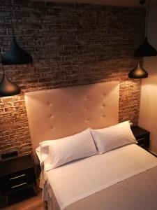 um quarto com uma cama branca e uma parede de tijolos em Alvarado Loft Rural em Ubrique