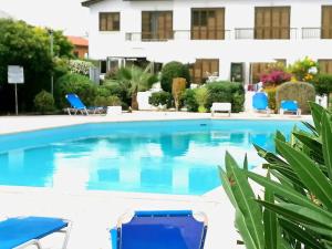 ein Pool mit blauen Stühlen und ein Gebäude in der Unterkunft Lisa's Apartment - Margarita Gardens in Paphos City
