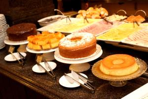 a buffet with different types of cakes and pastries at Carlton Plaza São José dos Campos in São José dos Campos