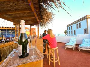 Eine Frau, die auf einem Stuhl am Tisch mit einer Flasche Wein sitzt. in der Unterkunft Casa Blanca Guest House Tenerife in Granadilla de Abona
