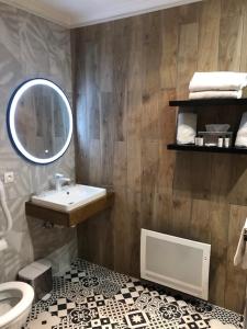 ein Bad mit einem Waschbecken und einem Spiegel in der Unterkunft Les Jardins d'Ulysse, The Originals Relais (Relais du Silence) in Stella-Plage