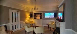 a living room with a television and white chairs at Sunnycroft Private Hotel in Llandudno