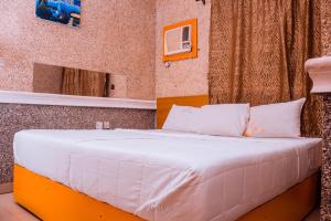 a bed with white sheets and pillows in a room at Double One Suites & Lodge in Ikeja