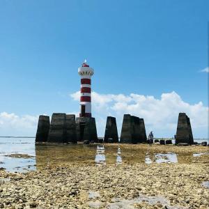 um farol vermelho e branco na praia em Pousada Águas Marinhas em Maceió