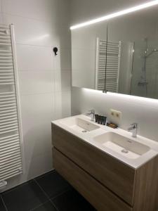 Baño blanco con lavabo y espejo en Appartement Anne-Rose, en Beernem