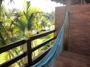 een hangmat op een hek met palmbomen bij Pousada Farol do Marinheiro in Boicucanga