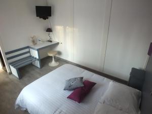 a bedroom with a white bed with two pillows on it at Hotel Restaurant Le Manguier in Peyrat-de-Bellac