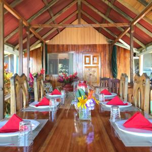 uma longa mesa de madeira com guardanapos vermelhos e flores em Casa Horizontes Corcovado em Drake
