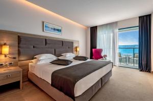 a bedroom with a large bed with a view of the ocean at Hotel Plaža Duće in Omiš