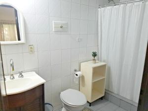 a bathroom with a toilet and a sink and a shower at Rosalia Suites in Loma Hermosa