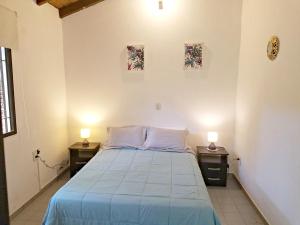 1 dormitorio con 1 cama con 2 lámparas en 2 mesas en Rosalia Suites en Loma Hermosa