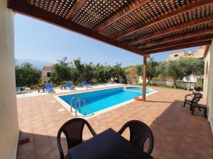 a patio with a pool and a table and chairs at Argo Villa Kalives in Kalyves