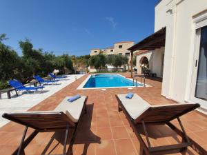 a swimming pool with two chairs next to a house at Argo Villa Kalives in Kalyves