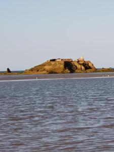 une grande étendue d'eau avec une île au loin dans l'établissement Appartement F1 mansardé à 100m de la plage, proche de Arromanches et des plages du Débarquement, à Saint-Côme-de-Fresné