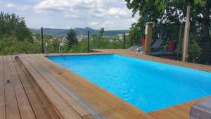 a large blue swimming pool with a wooden deck at Le gite@perché in Sainte-Marguerite