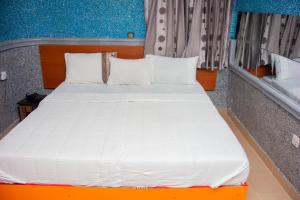 a bed with white sheets and pillows in a room at Double One Suites & Lodge in Ikeja