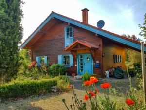 a wooden house with a blue door and red flowers at Malerisches Holzhaus "Coco" mit Kamin, Sauna und eigenem Garten in Kleinfischlingen