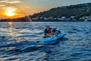 two people on a jet ski in the water at sunset at Hotel Plaža Duće in Omiš