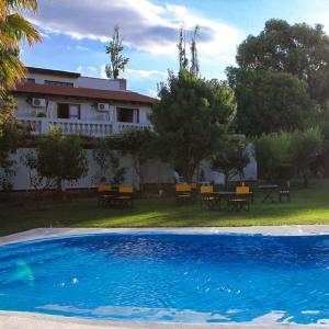 a swimming pool in front of a house with tables and benches at De Los Andes Hotel Boutique in Ciudad Lujan de Cuyo