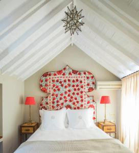 1 dormitorio con 1 cama blanca grande y cabecero rojo en Posada La Sacristía, en Tarifa