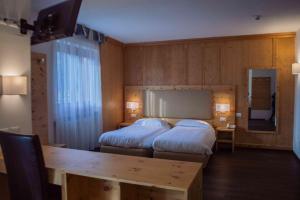 Habitación de hotel con 2 camas y mesa en Hotel Villa Fosine en Pinzolo