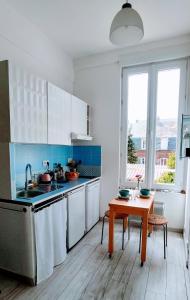 una cucina con mobili bianchi e un tavolo di legno di Studio 3 étoiles lumineux et calme à 250 m de la plage a Mers-les-Bains