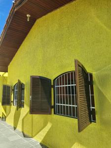 a yellow building with brown shuttered windows on it at Casa de Temporada Próximo a Praia in Caraguatatuba