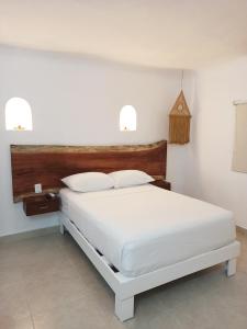 sypialnia z białym łóżkiem i zegarem na ścianie w obiekcie Hotel Caracol Puerto Morelos w mieście Puerto Morelos