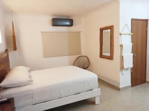 a white bedroom with a bed and a mirror at Hotel Caracol Puerto Morelos in Puerto Morelos