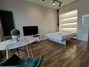 - un salon avec un lit, une table et une télévision dans l'établissement Nowoczesny Apartament z widokiem, à Varsovie