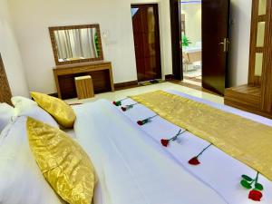 Duas camas num quarto com lençóis brancos e almofadas douradas em Olive Suites em Hail