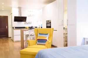 a yellow chair in a bedroom with a kitchen at Blonski-Yellow in Málaga