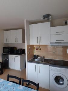 a kitchen with white cabinets and a washing machine at imperatrice eugenie in Luz-Saint-Sauveur