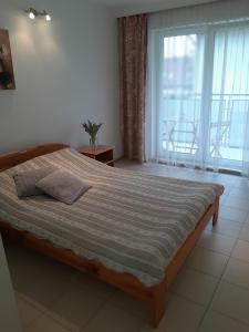 a bedroom with a bed and a large window at Maris Pokoje Gościnne in Łeba