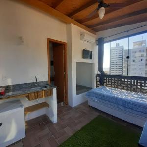a bathroom with a sink and a bed and a window at Suite confortável 5 in Florianópolis