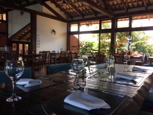 uma sala de jantar com uma mesa de madeira e copos de vinho em Hotel Cave do Sol em São Pedro da Aldeia
