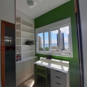 a green room with a desk and a window at Suíte confortável in Florianópolis