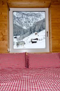 1 cama con una almohada roja y blanca a cuadros frente a una ventana en Casa vacanze Heidi e Peter Val di Rabbi, en Rabbi