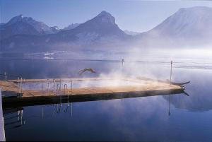 a bird flying over a dock on a lake with mountains at Romantik Hotel Im Weissen Rössl am Wolfgangsee in St. Wolfgang