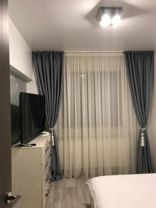 a bedroom with a bed and a tv and curtains at ELEGANT & SILVER LUXURY Apartament in Craiova