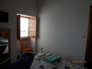 ein Schlafzimmer mit einem Bett, einem Fenster und einem Stuhl in der Unterkunft Adega Vermont in Biscoitos