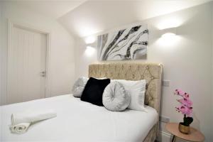 a white bed with black and white pillows at Two bedroom flat next ot brighton seafront sleep 6 in Brighton & Hove
