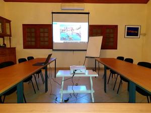 una sala de reuniones con dos mesas y una pantalla de proyección en Villa Charles - île de Gorée en Gorée