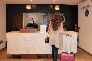 a woman wearing a face mask standing in front of a counter at Alou Hotel Boutique in Tijuana