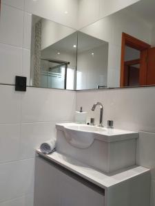 Baño blanco con lavabo y espejo en Apartamento 46 en Necochea