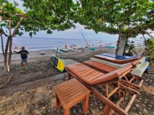 a man standing on a beach with a table and chairs at Solaluna Beach Homestay in Amed