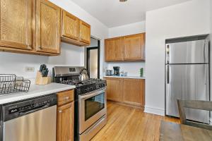a kitchen with wooden cabinets and stainless steel appliances at Your 1BR Homey Haven in Vibrant Chicago - Larchmont 1A-3A in Chicago