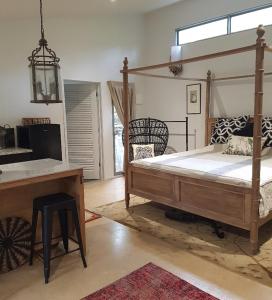 ein Schlafzimmer mit einem Himmelbett, einem Tisch und einem Schreibtisch in der Unterkunft Mt Lofty Botanic Garden Studio in Crafers