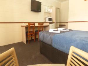 a room with a bed and a table with a microwave at Banjo Paterson Motor Inn in Townsville